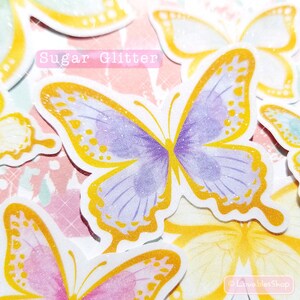 May include: A set of colorful butterfly stickers with a glittery finish. The butterflies are in shades of purple, pink, yellow, and blue. The text "Sugar Glitter" is printed on the sticker sheet.
