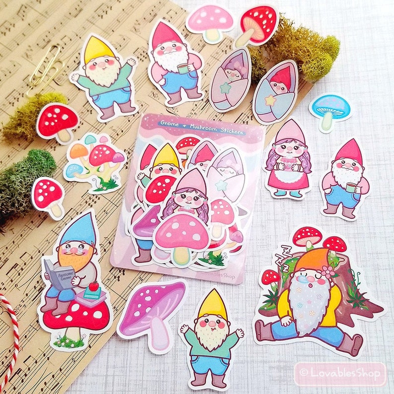 May include: A sheet of colorful gnome and mushroom stickers. The stickers feature gnomes with different expressions and outfits, including a gnome reading a book, a gnome wearing a yellow hat, and a gnome wearing a pink dress. The stickers also feature mushrooms in various colors and sizes.