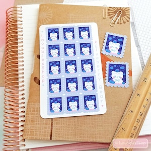 May include: A sheet of 12 stickers featuring a white bear wearing a blue bow and sitting on a blue and white cloud with blue stars. The stickers are arranged in a grid pattern and have a white border. The text "Blueberry Bear" and "Lovableshop" are printed on the sheet.