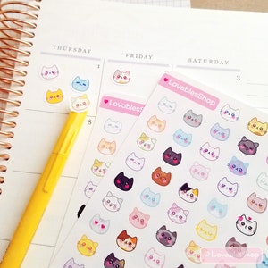 Op de afbeelding: Een vel met kleurrijke katten stickers met verschillende uitdrukkingen. De stickers zijn op een witte achtergrond en hebben een roze rand. De tekst "LovablesShop" is op het vel gedrukt.