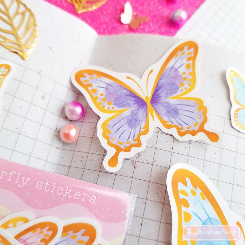 May include: A sheet of colorful butterfly stickers with a gold outline. The butterflies are purple, blue, and yellow. The sheet has the text "butterfly stickers" printed on it.