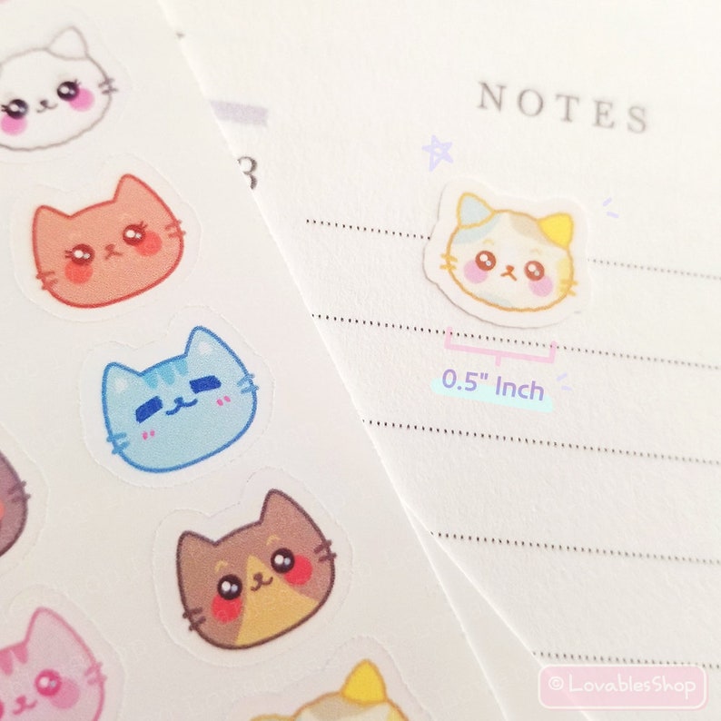 Op de afbeelding: Een vel met kleurrijke katten stickers met verschillende vachtkleuren en gezichtsuitdrukkingen. De stickers hebben een diameter van 1,27 cm. NOTES staat bovenaan de pagina.
