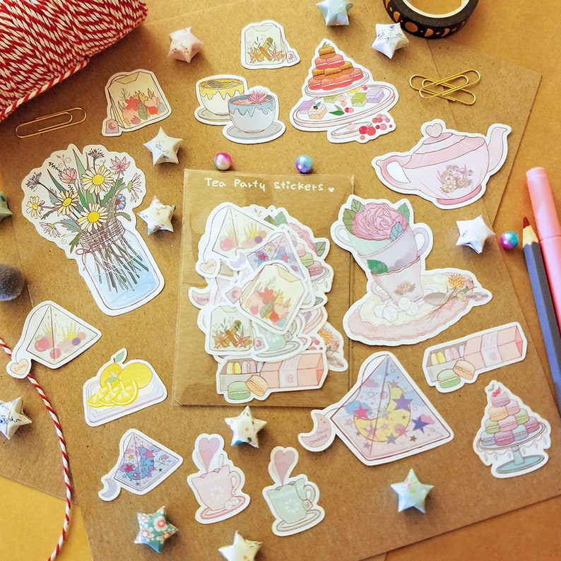 May include: A sheet of colorful stickers featuring tea party themed illustrations. The stickers include teacups, teapots, tea bags, lemons, flowers, and a moon and stars design. The text "Tea Party Stickers" is printed on the sheet.