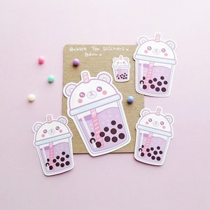 Puede incluir: Cuatro pegatinas con un oso de dibujos animados que lleva una taza de t&eacute; de burbujas rosa y blanca. Las pegatinas est&aacute;n sobre un fondo marr&oacute;n con el texto "Bubble Tea Stickers" y "Bear" escrito en negro.