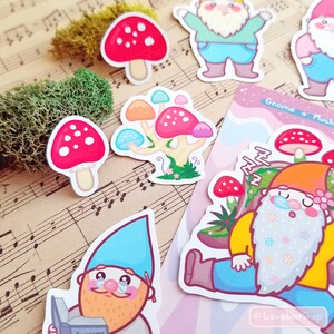May include: A set of colorful gnome and mushroom stickers. The stickers feature gnomes wearing blue and yellow hats, red and white mushrooms, and a mushroom cluster with pink, blue, and white mushrooms. The stickers are perfect for adding a whimsical touch to journals, laptops, water bottles, and more.