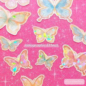 May include: A sheet of holographic butterfly stickers with a pink glitter background. The butterflies are in various shades of blue, pink, and orange.