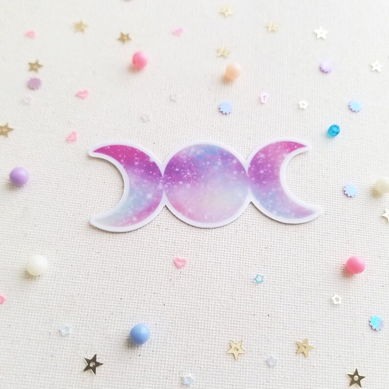 May include: A triple moon symbol sticker with a galaxy design in shades of pink, purple, and blue.