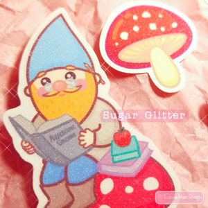 May include: A cartoon gnome wearing glasses and a blue hat sits on a red and white mushroom. The gnome is holding a book titled "Advanced Gnome" and has an apple on a stack of books next to him. The image has a sparkly, glittery texture.