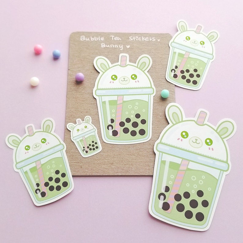 Puede incluir: Cuatro pegatinas de t&eacute; de burbujas verdes con una cara de conejo blanco en la tapa. El texto "Bubble Tea Stickers Bunny" est&aacute; sobre un fondo marr&oacute;n.
