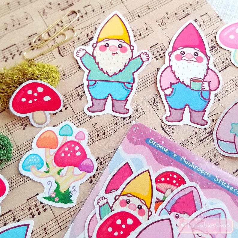 May include: A sheet of colorful stickers featuring gnomes and mushrooms. The stickers are on a sheet of paper with musical notes printed on it. The stickers are in a variety of colors, including red, blue, yellow, green, and pink. The text "Gnome & Mushroom Stickers" is printed on the sheet of paper.