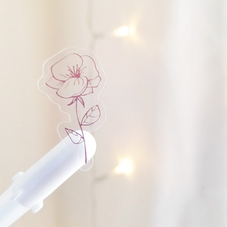 May include: A clear sticker with a pink outline of a single flower with leaves.