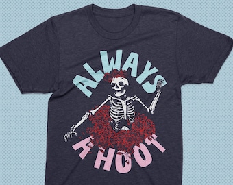 May include: A dark blue t-shirt with a graphic of a skeleton wearing a flower crown and surrounded by roses. The text "ALWAYS A HOOT" is printed in pink around the skeleton.
