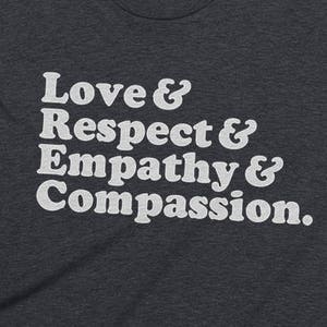 May include: A dark heather grey t-shirt with white text that reads "Love & Respect & Empathy & Compassion."