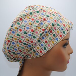May include: A beige scrub hat with a colorful light bulb pattern. The hat has a tie at the back.