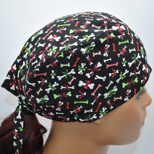 May include: Black scrub hat with a white bone and red and green bow pattern.