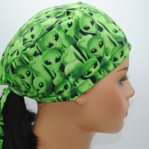 May include: Green surgical scrub hat with a repeating pattern of green alien faces.