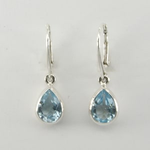 May include: A pair of silver teardrop earrings with light blue gemstones.