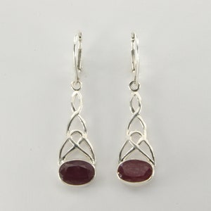 May include: A pair of silver dangle earrings with a red oval gemstone set in a Celtic knot design.