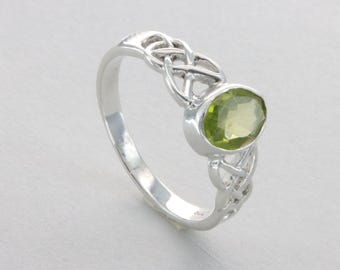 May include: A silver ring with a green peridot gemstone set in a Celtic knot design.