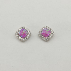 Puede incluir: Un par de pendientes de plata con una piedra de ópalo rosa de forma cuadrada rodeada por un halo de piedras de circonita cúbica transparentes.