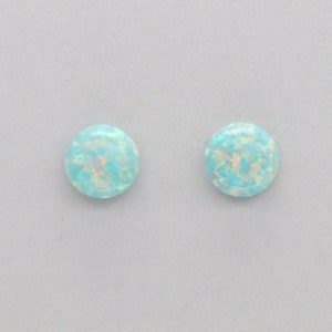 May include: A pair of round opal earrings with a light blue and white iridescent finish.