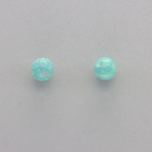 May include: A pair of small, round, light blue opal earrings.