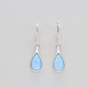 May include: A pair of silver-tone drop earrings. Each earring features a teardrop-shaped, light blue opal stone set in a silver bezel. The earrings have a lever-back closure.