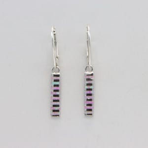 May include: A pair of silver-toned earrings with a rectangular, vertical design. Each earring features a series of small, rectangular, iridescent stones in shades of pink, purple, and white, set in a linear pattern.
