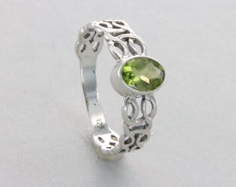 May include: A silver ring with a green peridot gemstone set in a Celtic knot design. The ring is marked with the number "125".