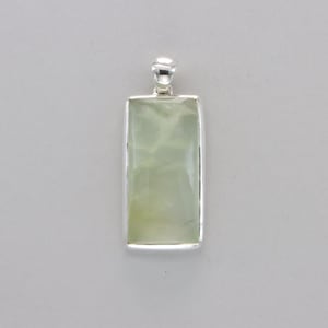 May include: A silver pendant with a light green rectangular stone.