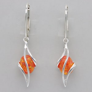 May include: A pair of silver dangle earrings with orange opal stones set in a swirl design.