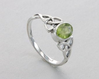 May include: A silver ring with a green peridot stone set in a Celtic knot design.