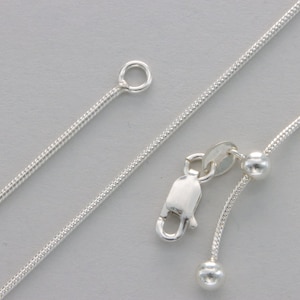 May include: A silver snake chain necklace with an adjustable length. The necklace has a lobster clasp and two small silver beads.
