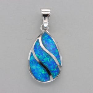May include: A teardrop-shaped pendant with a silver setting and a blue opal inlay. The opal has a swirling pattern.