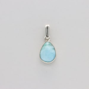 May include: A teardrop-shaped pendant with a light blue stone and a silver-colored metal setting. The stone has a marbled appearance with shades of blue and white. The pendant is designed to be worn as a necklace.