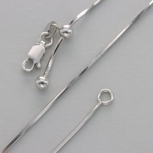 May include: A silver chain necklace with a lobster clasp and two small round beads. The chain is a snake chain style.