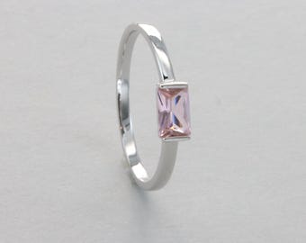 May include: A silver ring with a rectangular pink gemstone.