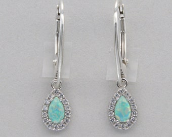 May include: A pair of silver dangle earrings with a teardrop-shaped opal stone surrounded by a halo of smaller clear stones.