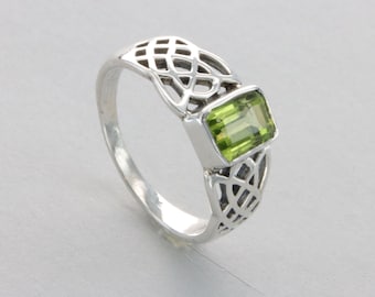 May include: A silver ring with a green gemstone set in a Celtic knot design.