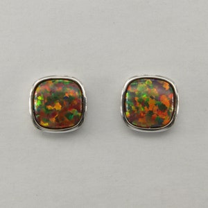 Puede incluir: Un par de pendientes cuadrados de plata con una piedra de ópalo de colores en el centro de cada pendiente.