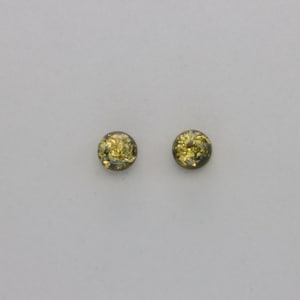 May include: A pair of small, round, green and gold amber stud earrings.