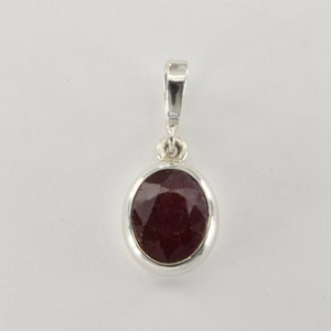 May include: A silver pendant with a red oval gemstone.
