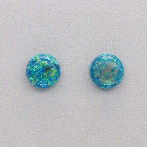 May include: A pair of round, blue opal earrings with a glittery, iridescent finish.