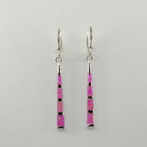 May include: A pair of silver dangle earrings with pink opal stone accents. The earrings have a long, thin, tapered shape.