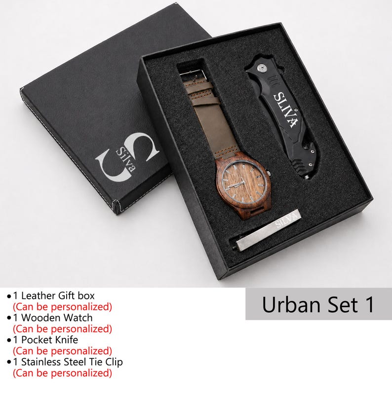 May include: A black gift box set containing a wooden watch with a brown leather strap, a black pocket knife, and a silver tie clip. The watch face has a wood grain design. The box is labeled "Silva" and "Urban Set 1".
