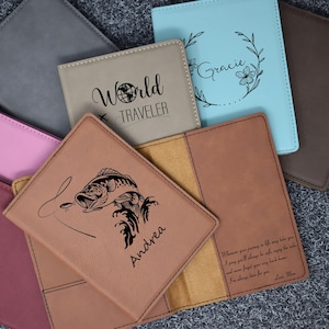 May include: A set of six passport holders with different designs. The designs include a world map with the text "World Traveler", a fish jumping out of the water, a floral wreath with the text "Gracie", and a quote about journeys in life.