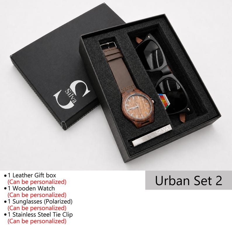 May include: An open black gift box set containing a wooden watch with a brown leather band, black sunglasses, and a silver tie clip. The watch face has a wood grain design. The box is labeled "Silva" and "Urban Set 2".