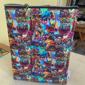Pode incluir: Uma bolsa com zíper colorida com um padrão repetitivo de esqueletos, navios e edifícios. A bolsa tem um zíper preto e um puxador de zíper dourado.