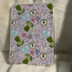 May include: A lavender phone case with a clear border, featuring a repeating pattern of green jerseys with the number 13, hearts, and text that reads "For Keeps," "Tommen College," and "Kavanagh 13."