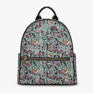 Peut inclure: Un sac à dos turquoise avec un motif répété de tasses à thé, de roses, de champignons, de cristaux, de livres et de lunes. Le sac à dos a une poignée, une fermeture éclair et une garniture noires. Le sac a deux poches latérales et une poche avant zippée.